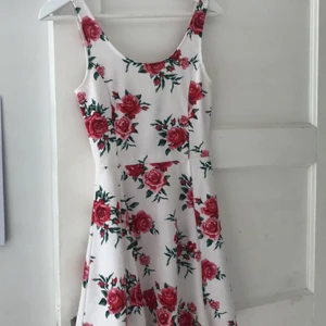 Blommig klänning från H&M - Klänning köpt från H&M 2018. Använd ett antal gånger men i bra skick. Vit med rosor. Storlek 34. Köpare betalar frakt 
