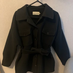 Svart kappa från Nelly storlek 36 - En svart kappa från Nelly storlek 36, den är stor i storleken. Köpt hösten 2021, använt fåtal gånger. Så kappan är i bra skick. 