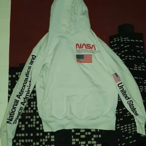  Vit Nasa hoodie med tryck på bröstet och ärmarna - Säljer denna hoodie då den är för liten för mig. Bra material och väldigt skön! Inga hål eller fläckar. Storlek M. Pris kan prutas vid snabb affär. 