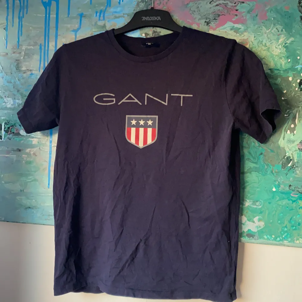 Marinblå T-shirt från Gant köpt på kidsbrandstore.se. Storlek 158-164cm, men passar lika bra på en med storlek S. Inköpt för ca 2 år sedan, och har använt den under 1 sommar. Överlag fint skick trots att den är använd. . T-shirts.