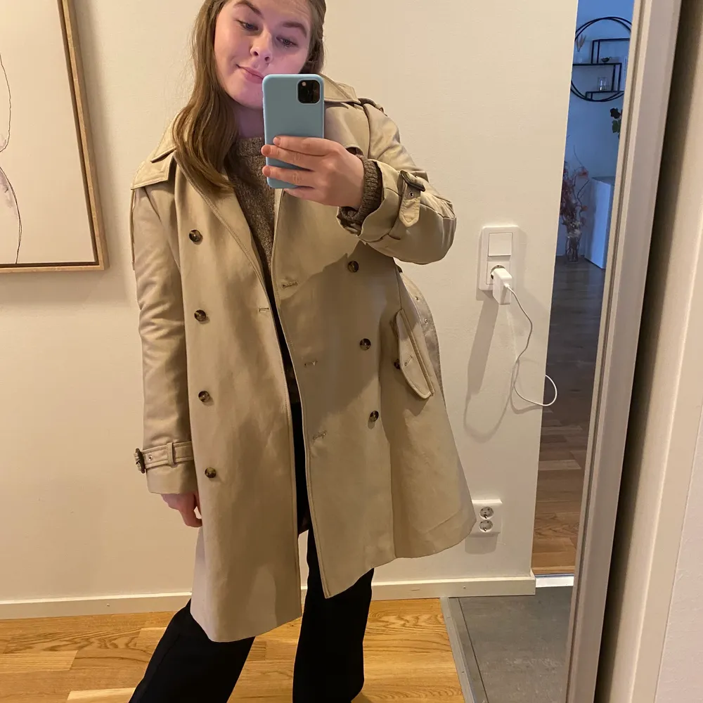 Rejäl och snygg trenchcoat från Zara i strl L (mer som S-M). Väldigt fint skick, men har dock några svarta streck på knytningen (bara skriva om ni vill se bild). Annars i fint skick. Trenchcoaten har en luva, men den går att ta av. På första bilden bärs den av en xs-s o på andra en M. Säljs för 266kr inkl frakt🤍🤍. Jackor.