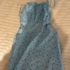 Klänning - Superfin sommarklänning i en ljusblå färg med blommar och en superfin detalj i ryggen passar perfekt till midsommar eller bara en varm sommardag 🥰