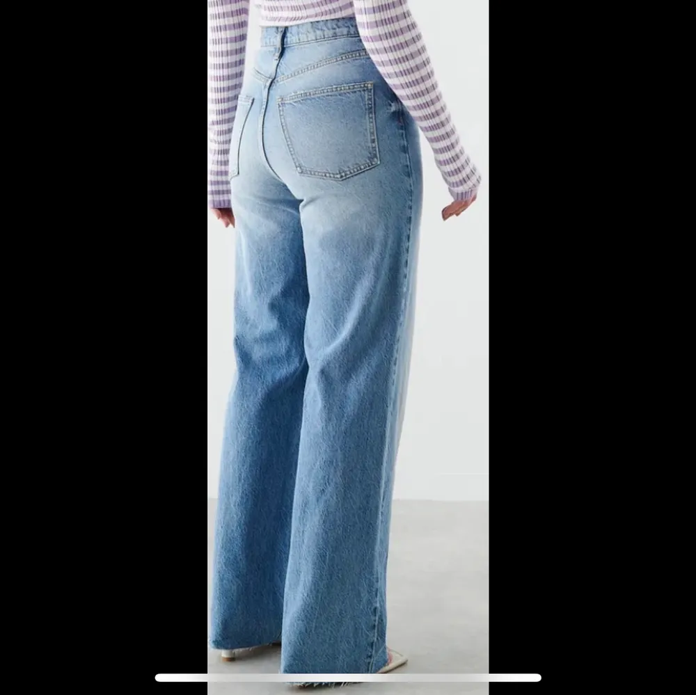 Petite jeans med superhög midja. Jeansen är blåa och utan stretch och har raka, vida byxben med fullängd. De har dragkedjegylf och rå kan vid bensluten. . Jeans & Byxor.