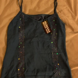 Oanvänt blått linne med paljetter  - Jättefint linne från humana som aldrig använts av mig. Prislappen finns kvar. Det står ingen storlek men den är strechig och kan passa allt från xs-l 