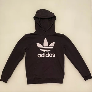 Svart Adidas hoodie - En svart Adidas originals hoodie i storlek 152. Hoodien har tyvärr ett igensytt hål på undersidan av den vänstra ärmen men är övrigt i gott skick. Hoodien funkar för både tjejer och killar. Den kan skickas eller mötas upp i linköping.