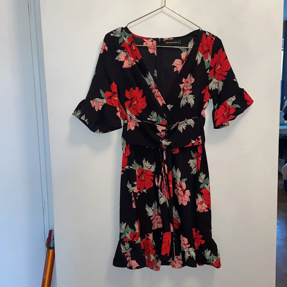 En blommig klänning från PrettyLittleThing med korsettliknande bälte runt midjan. Aldrig använd.. Klänningar.