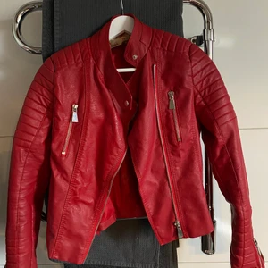 Röd skinnjacka - Plagget är i storlek 38 men passar nog bäst S/XS. Super nice jacka och är i bra skick för att vara så gamal. Den har dock en lagning på innersidan av ryggen men ingenting man lägger märket till. Ej äkta skinn. Ny pris är någonstans mellan 1000-2000kr