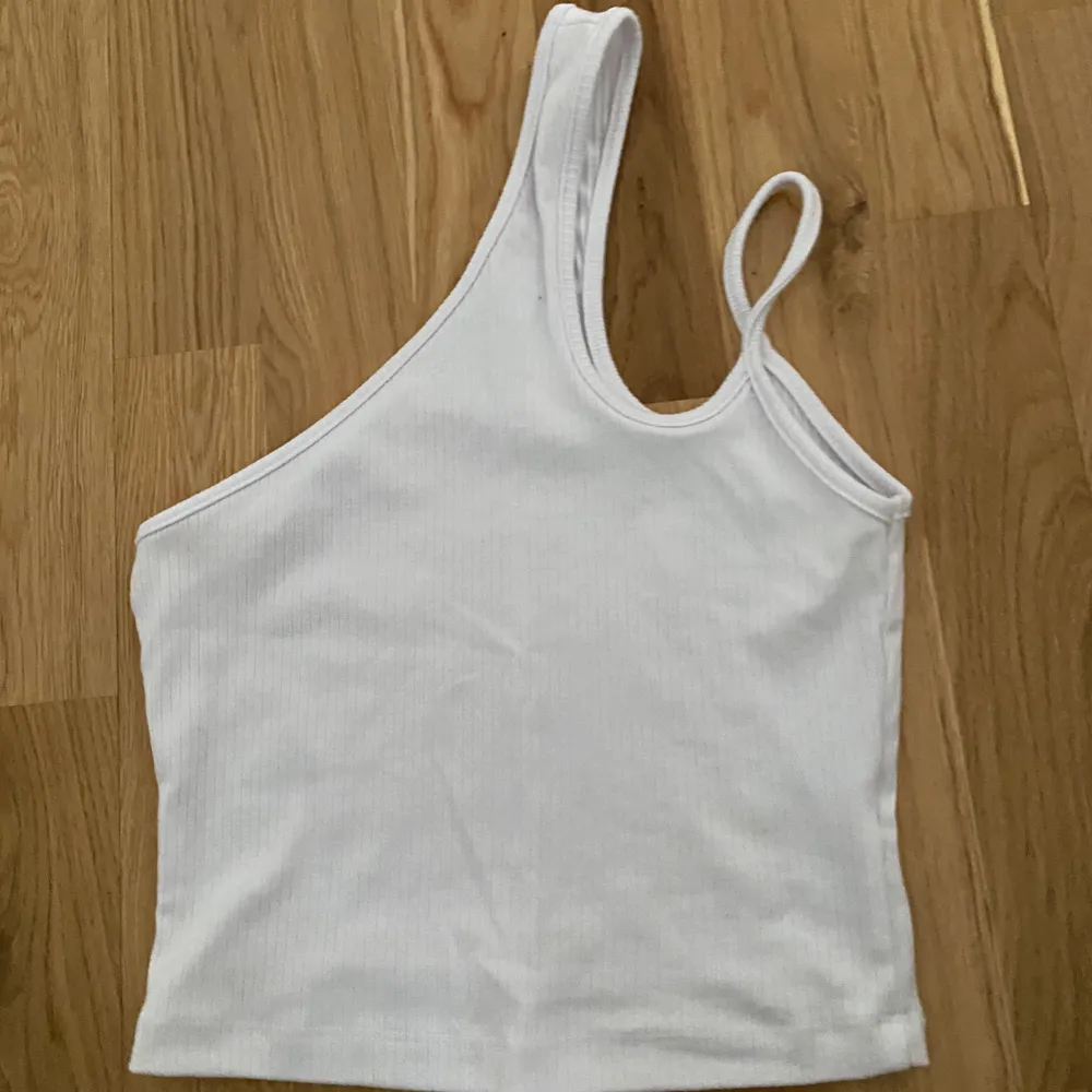 Vit ribbad, one shoulder top från Bershka i strl. S. Aldrig använd men prislappen har tagits av. Fungerar bra med nipple covers. . Toppar.