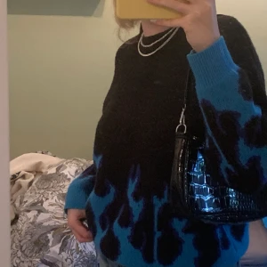 Stickad Tröja - Stickad tröja med blåa eldflammor, endast använd 1-2 gånger (alltså väldigt bra skick). Passar perfekt till jeans eller kjol nu till våren💗🌸