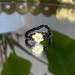 Svart ring med blomma, egentillverkad! 🖤                   Passar S-M                                                                          Säljer för 15kr + 12kr i frakt. Fraktpriset är det samma oavsett antalet ringar man köper ✨