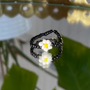 Svart ring med blomma  - Svart ring med blomma, egentillverkad! 🖤                   Passar S-M                                                                          Säljer för 15kr + 12kr i frakt. Fraktpriset är det samma oavsett antalet ringar man köper ✨