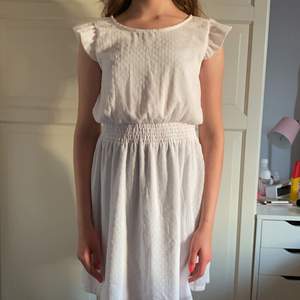 En vit somrig klänning strl 158 med ett prickigt material. Lite puffiga volangärmar och ett resorband i mitten. frakt ingår:) Tvättar såklart innan frakt.
