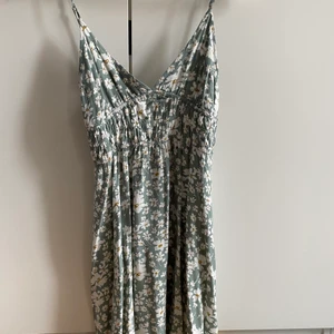 Blommig klänning - Grön klänning med vita och gula blommor på. Den är ifrån Nelly, storlek S. Köparen står för frakten🤍