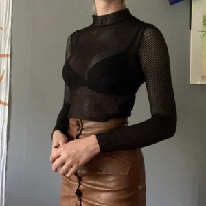 Fishnet top svart - Svart fishnettröja med hög krage. Älskar denna. Har dragit mig för att sälja den men använder den aldrig!! Kjolen i bilden säljer jag också. Frakt tillkommer. 