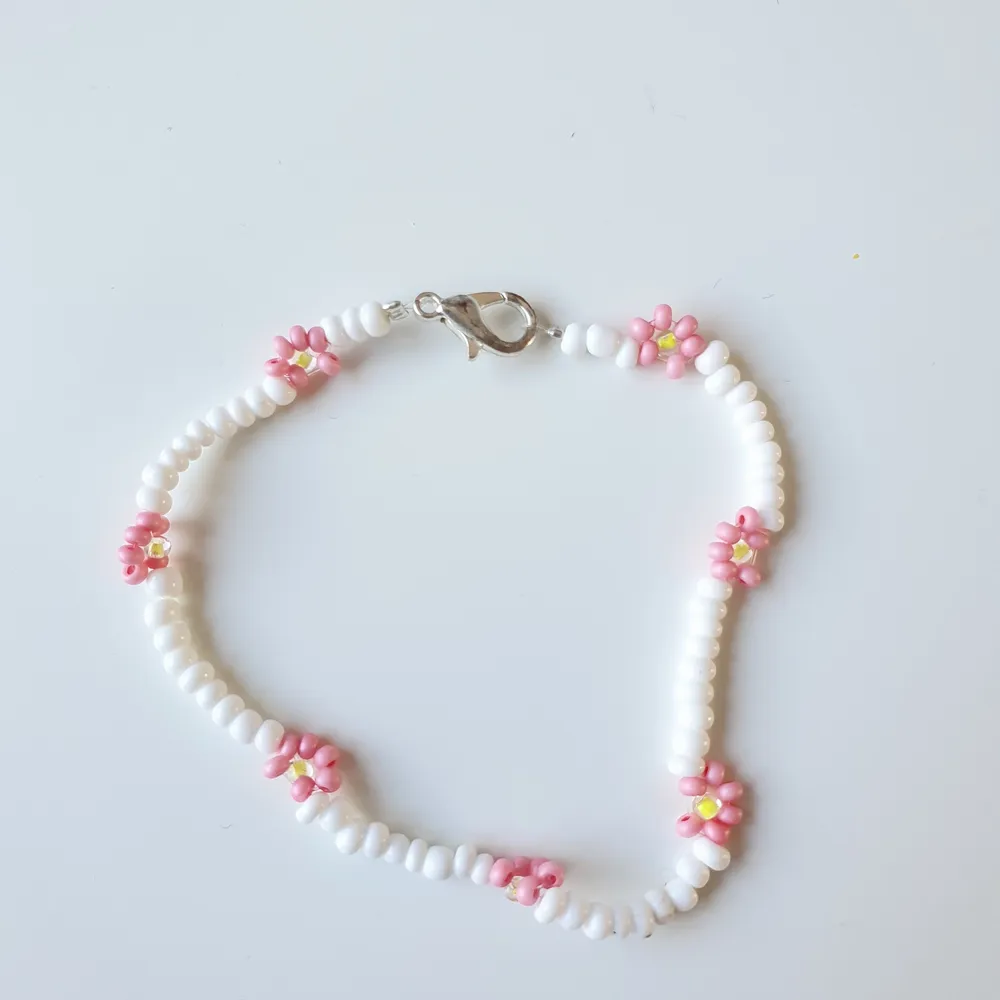 Vitt armband med rosa blommor 🌸🌸🌸. Accessoarer.