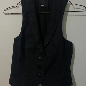 Svart trendig väst - Snygg och trendig, vintage väst i ett mjukare jeans material från gina tricot. Köpt men aldrig använd pga att jag redan har två andra. Storleken som står är 34 men skulle säga att den passar allt från 32-36 beroende på passform. Skriv privat ifall du har fler frågor!