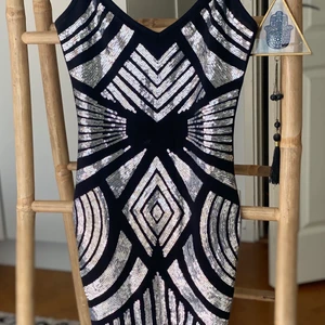 Klänning - Klänning med silvriga paljetter, baksidan är helt svart. Den är kort. Storlek XS.