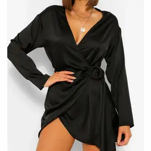 En svart omlottklänning i satin från boohoo. Väldigt fin klänning med spänne så man kan anpassa passformen. Aldrig använd då den var något kort för mig, är 175cm lång. Annars sitter den väldigt fint! 