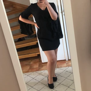 Svart klänning med knytning - Svart klänning med knytning i midjan. Superfin på med fina detaljer i armarna. Aldrig kommit till användning. V-ringning. 