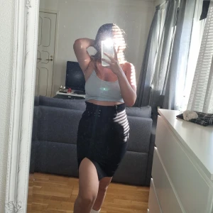 Svart kjol med skärp från New Yorker - En längre och högmidjad svart kjol från New Yorker, bara använd några få gånger, så sparsamt använd. Tajt passform. Med skärp och dragkedja på sidan, och slits