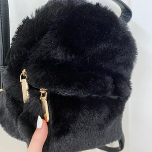 Fluffig miniryggsäck - Säljer denna super fluffiga miniväskan med gulddetaljer då jag inte andvänder den. Andvänd en eller två gånger så den är i nyskick💗 kontakta mig vid frågor💗