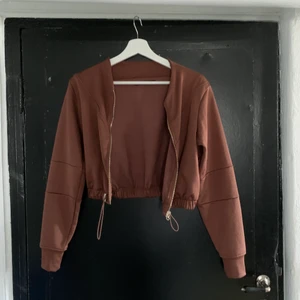 Croptop - Fin hoodie, ganska kort men man kan själv välja hur tajt i midjan den ska sitta. Guldetljerna är jätte fina mot de brun/lila tyget, sömmarna som går snett över bröstkorgen gör att den sitter hur fint som helst