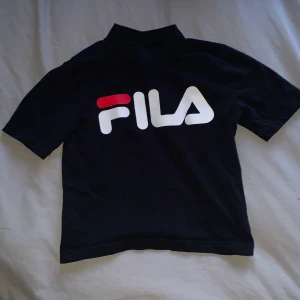 Cropped Fila tröja - En magtröja från FILA i väldigt bra skick. Har en halv polokrage, samt detalj att det även står FILA i nacken. Storlek S men passar nog XS också. Finns i Växjö annars tillkommer frakt💜 Endast swish!
