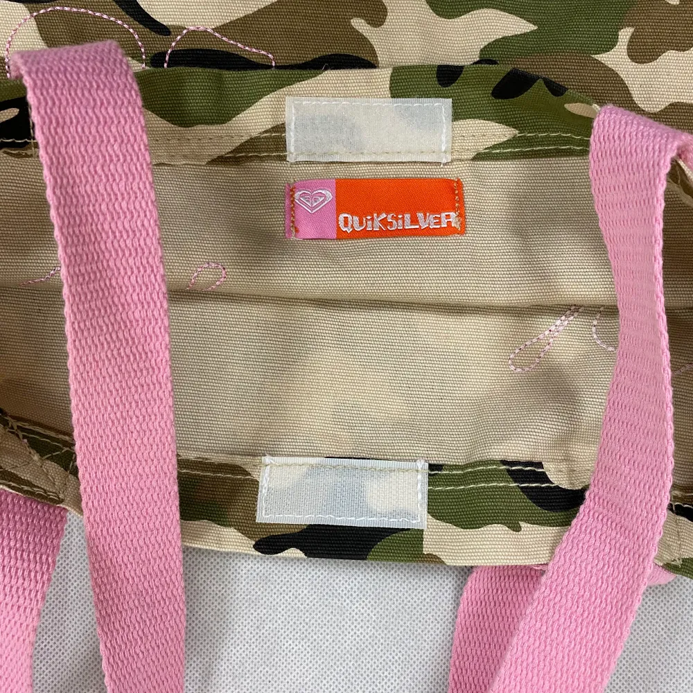 Supersöt y2k inspirerad tote bag från Quicksilver. I toppenskick! Camoflauge print med rosa 🌺 på båda sidorna. Längd (mätt utan rosa handtaget) 39cm och bredd  35cm. Väskor.