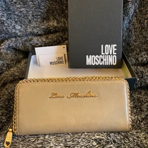 Love Moschino Plånbok  - Säljer plånbok från Moschino, beige. Lite smutsigt från begagnat. Dammpåse inkluderar.
