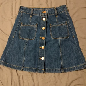 Jeanskjol - Supersnygg kort jeanskjol med bronz knappar framtill!