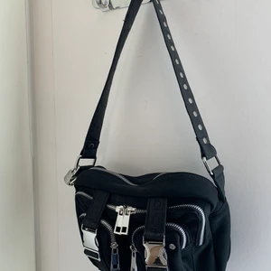 NuNoo väska Ellie scuba - En väska från märket NuNoo, modellen heter Ellie Scuba.  Jag köpte den för 900kr men säljer den för 500:- då den är i nyskick och använts vid två tillfällen.  - axelrem medföljer som syns på bilden - två fack på insidan ena med dragkedja -tre fack på utsidan med dragkedja  Bredd: 24,5 cm Höjd: 15 cm Djup: 8 cm 