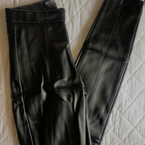 Fake läder byxor - Finns en liten slitts på båda sidorna längst ner och dragkedja för att sättas på 