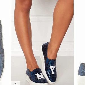 Steve Madden slip on  - Snygga blå glittriga Steve Madden skor med loggan ”N & Y”🤩 Är som nya då jag bara använt dom MAX 2 gånger!! Säljer pga ingen användning för dom.          Nypris ligger mellan 900- 1000kr, men buda från 700kr.                                                                  ❗️Skriv till mig vid intresse❗️