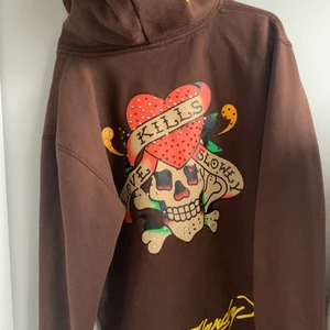 Ed hardy hoodie  - Snygg hoodie från ed hardy med rhinestones. Några av stenarna har ramlat! Väldigt fint skicka annars. Snygg brun färg. Storlek L i damstorlek så typ S/M i män. 