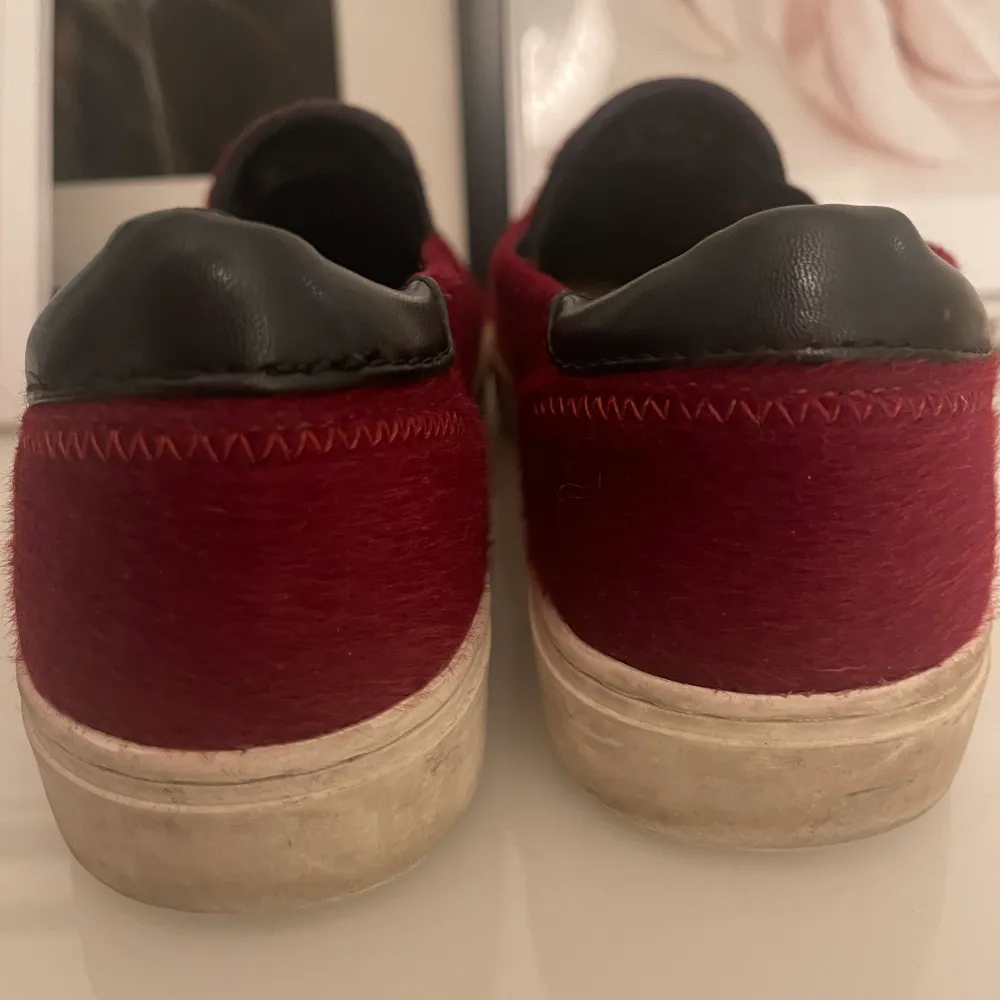 Vinröda sneakers med svarta detaljer i ett material som är ”hårigt” skorna är använda men fortfrande i fint skick! . Skor.