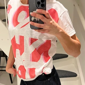 Coster copenhagen T-shirt - Oanvänd snygg T-shirt från bästa Coster! Dyr! Snyggt mönster med tryck i rött och rosa skugga på vit bas. Har knut i sidan som går att knyta upp till vanlig modell. Stlk S! 
