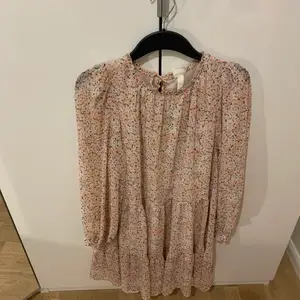 En slutsåld rosa blommig klänning från H&M som varit oerhört populär. Använd endast en gång. Nyskick. Storlek 34 men passar även 36 och kanske 38. Väldigt fin och flowy och skön. Går även att ha kortare armar då det är resår längst ned och man kan dra upp och ”lägga in” vid armvecken. Snygg både sensommar, sommar & vår. 