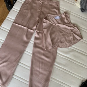 Co-ords / Två delat set  - Säljer ett två delat set i siden, ljusrosa, byxor i strl 38, top i strl 36. Säljs för 100kr, frakt tillkommer!
