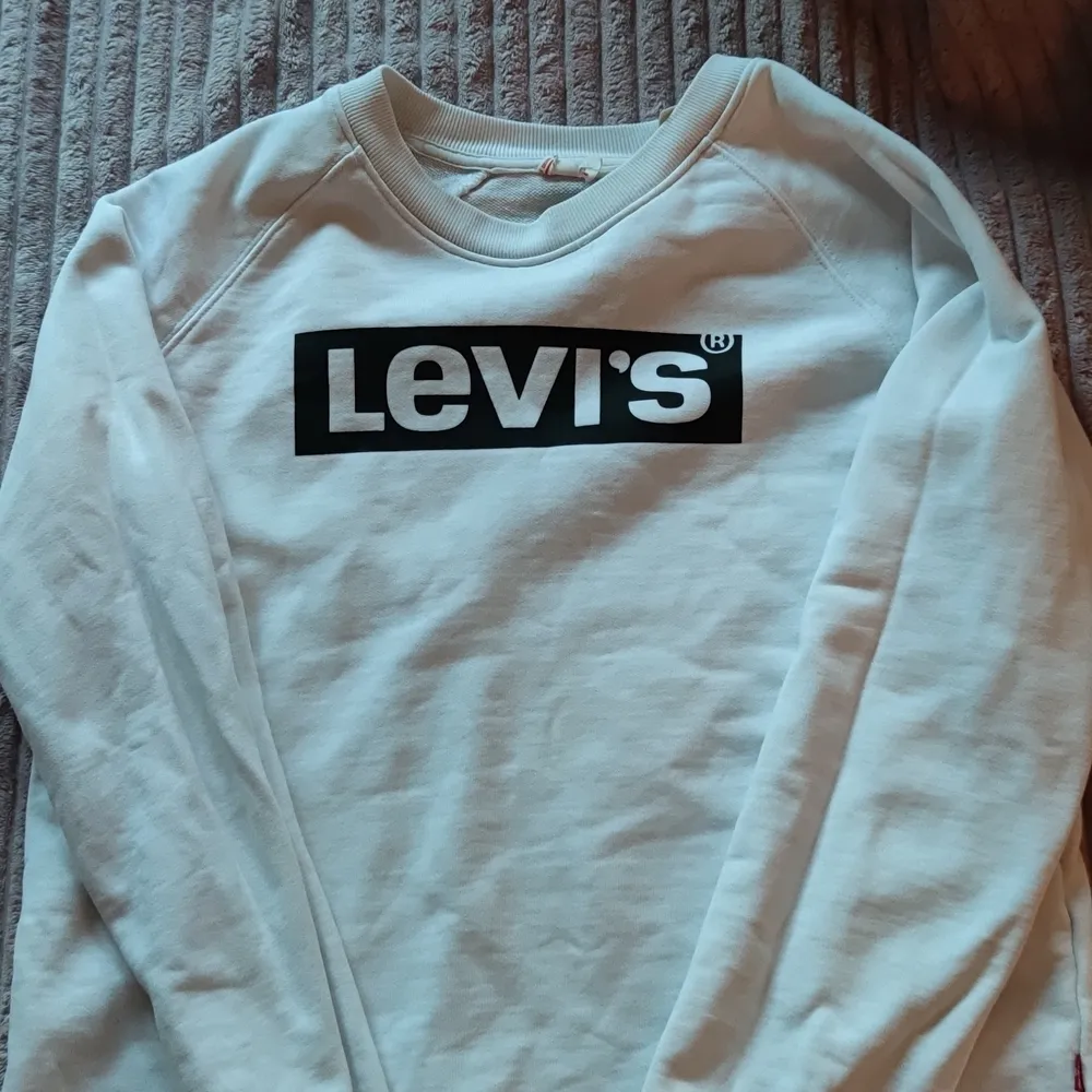 Vit tjockare Levis tröja i storlek S är lite uttvättad då den är använd mycket men i gott skick.  . Hoodies.