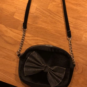 Väska - Okej skick,lite sliten vid rosetten, långt axelband. Perfekt nu till sommaren eller om man ska gå på en fest eller liknande, köp via Swish och frakt tillkommer!!✨🌸❤️ OBS: (frakt är uträknad efter vikt, alltså inget pris jag hittat på)