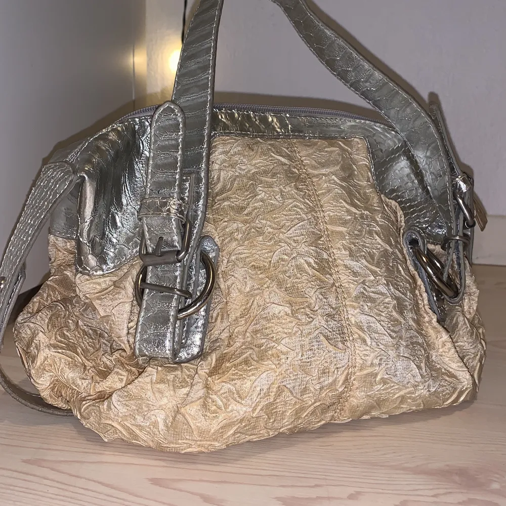 En söt  beige handväska med silverfärgade band. 21x27. Väskor.