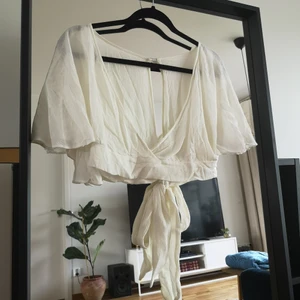 Vit blus med knytning i ryggen - Vit kort blus med knytning i ryggen inköpt i Asien. Använd ett par gånger men i hyffsat fint skick! Jag på bilden är 170 cm lång och har vanligtvis S/M i toppar. Ingen storlek eller märke på toppen, men uppskattas till S.