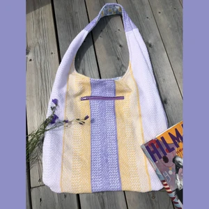 Lila, gul och vit frotté+blommig tygväska  - En så somrig tygväska jag sytt själv av enbart second hand material. Den är vändbar och är av mönstrad frotté på ena sidan med dragkedjsficka och ett blommigt bomullstyg på andra sidan med två stora innerfickor. Mer bilder på instagram @avpermert 
