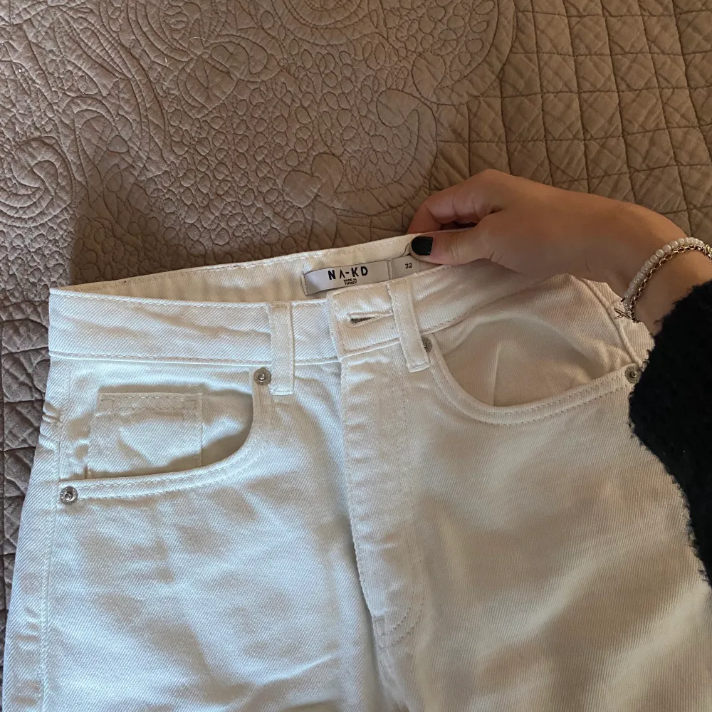 Jag säljer dessa högmidjade vita jeans från NAKD. Använda en gång, storlek 32, passformen är rak men lite bredare ner mot benen.. Jeans & Byxor.
