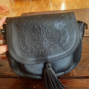 Väska - Snygg svart väska med deciratiba detalier. Axel band saknas