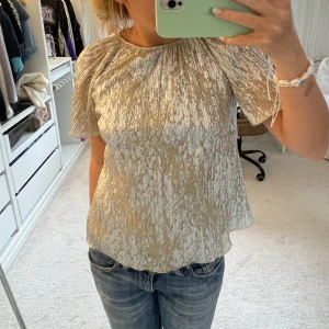Glittrig topp - Säljer denna blus/topp i guld och silvrigt mönster!!