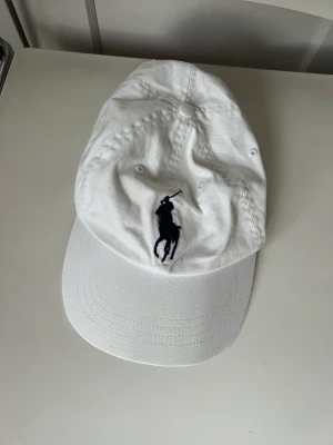 Ralph lauren keps  - Säljer en vit äkta Ralph lauren keps. Vit med blåa detaljer.