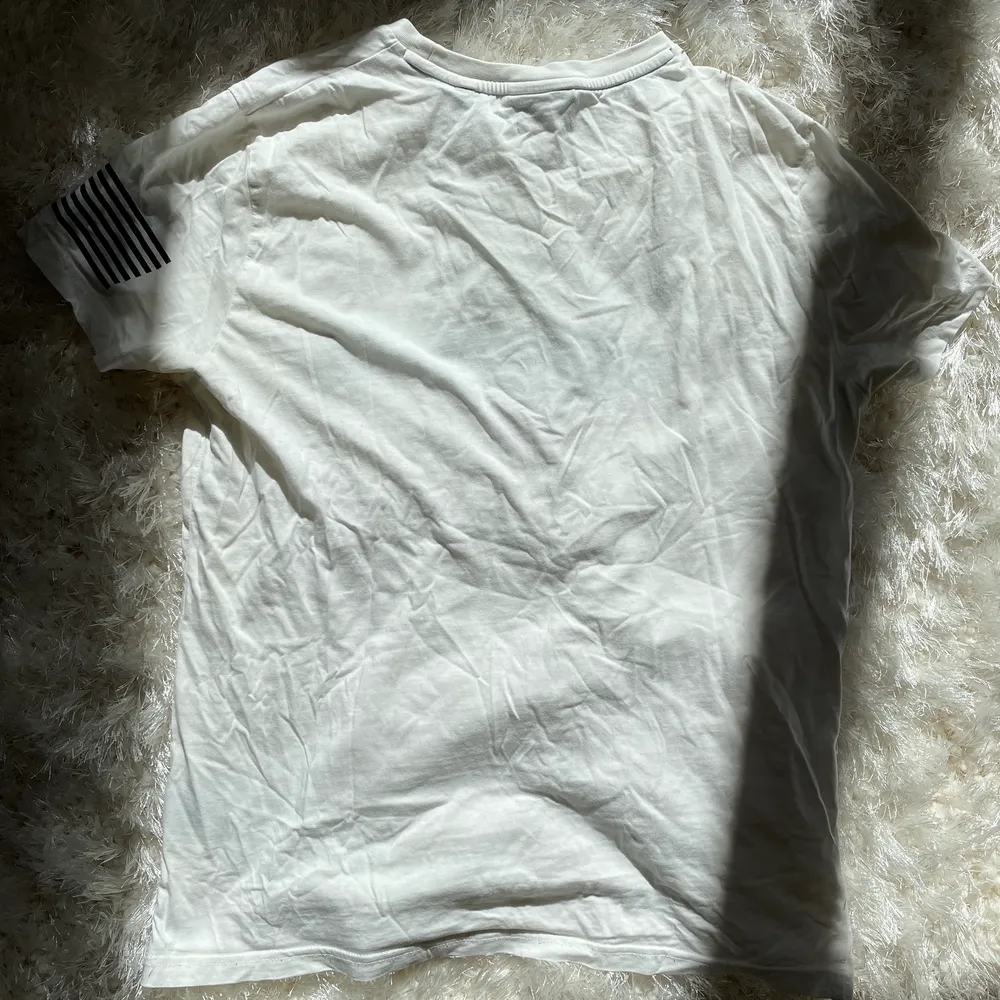 Vit t-shirt från GANT med marinblått tryck. Tröjan är i nyskick och har endast används ett fåtal gånger. . T-shirts.