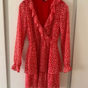 Volangklänning - Säljer denna superfina volangklånningen, röd med vita blommor. Den är använd några gånger men är i ett mycket fin skick. Passande till sommaren🤍
