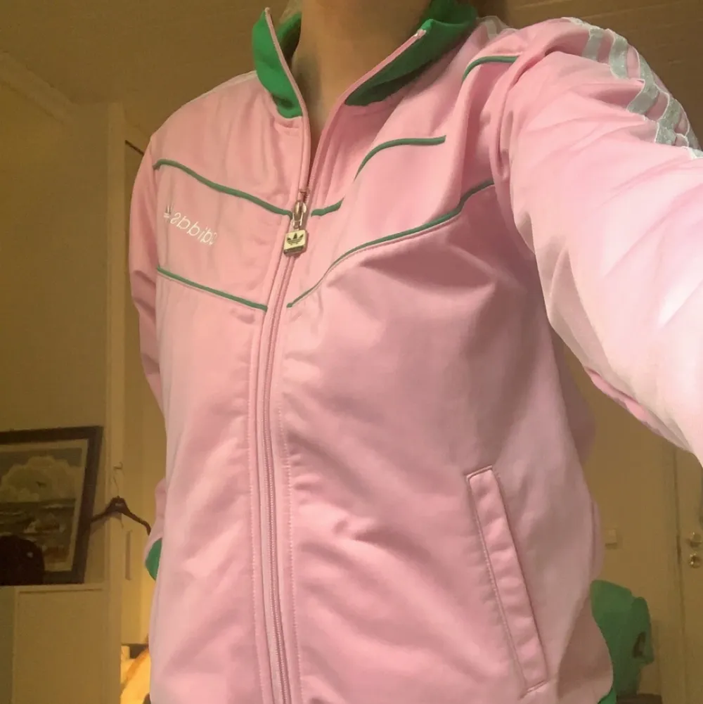 Super snygg  rosa Adidas jacka med gröna och vita detaljer köpt från sellpy, säljer pga att jackan inte riktigt är min stil! Jag själv har aldrig fått någon nytta av jackan. För fler bilder skriv gärna! 🤩 Pris går att diskuteras. Jackor.